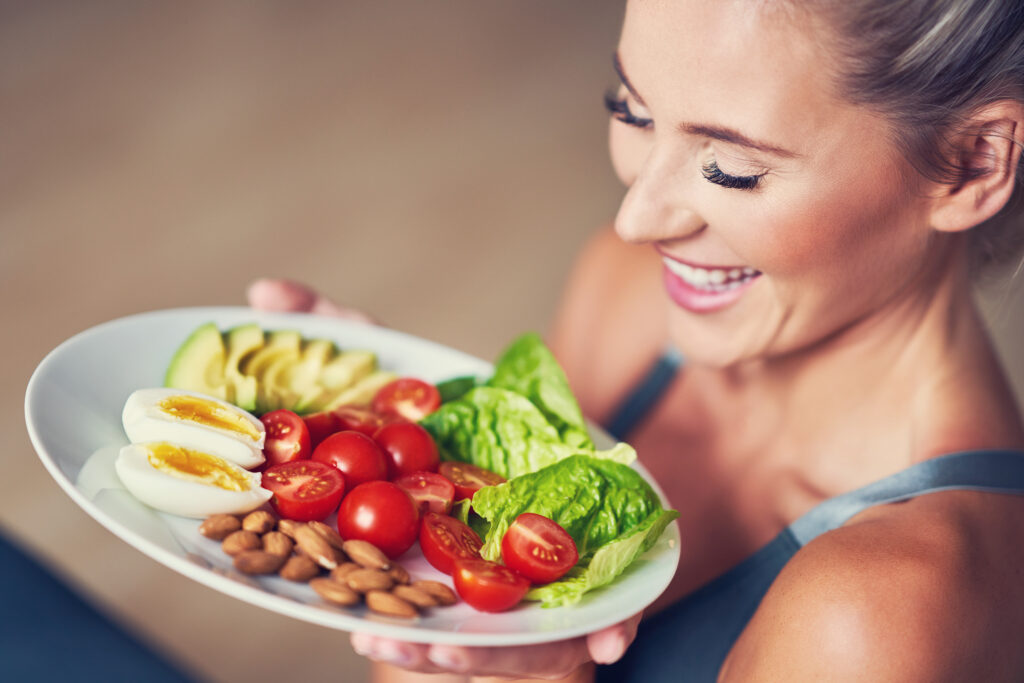 adult woman eating healthy lunch and sitting on yoga mat